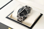 Unique wristwatch with intricate silver cage design and black dial displayed on white cushion