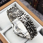 Close-up of ornate silver watch band with intricate embossed floral and swirl patterns