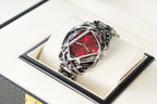 Stylish red dial wristwatch with intricate metal cage design in black leather watch box
