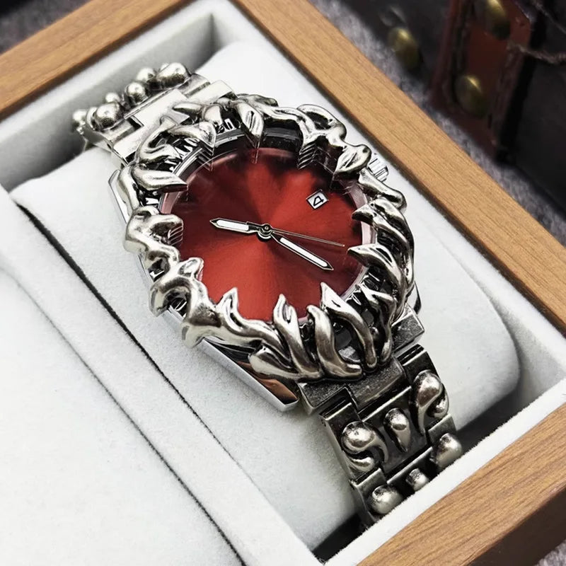 Silver metal wristwatch with red sunburst dial and ornate flame design bezel in wooden display box